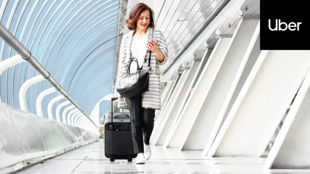 image of a woman walking out of an an airport booking a ride using Uber app