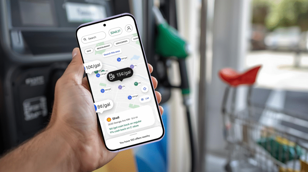 Hand holding smartphone with cashback notification near a gas pump and grocery cart, representing cashback for saving challenges.